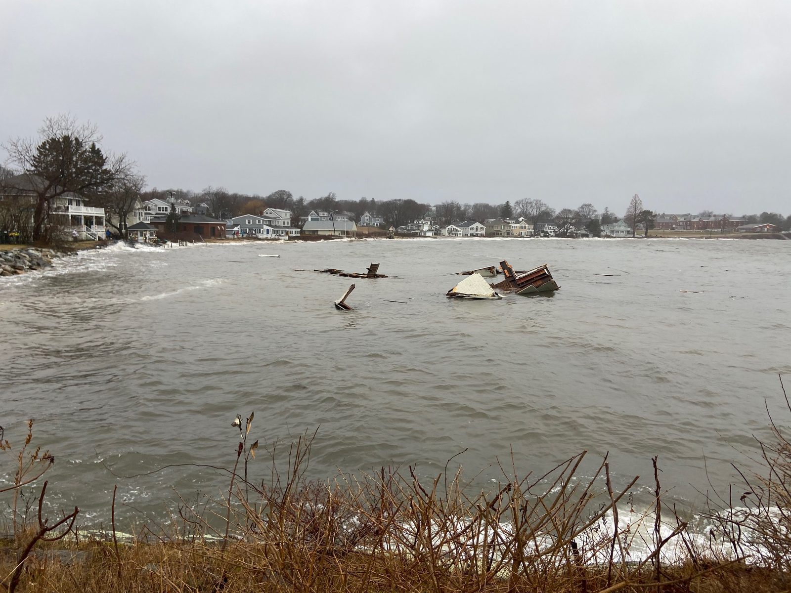 Flooded coastal street in South Portland with a boat pushed up onto the shore